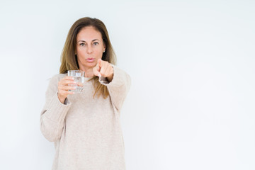 Middle age woman drinking glass of water isolated background pointing with finger to the camera and to you, hand sign, positive and confident gesture from the front