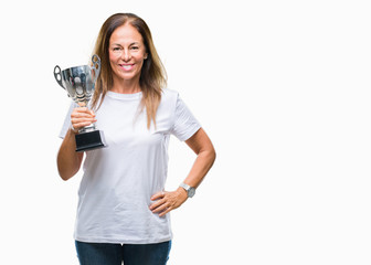 Middle age hispanic winner woman celebrating award holding trophy over isolated background with a happy face standing and smiling with a confident smile showing teeth