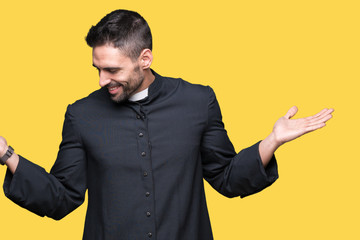 Young Christian priest over isolated background Smiling showing both hands open palms, presenting...