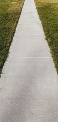 Perspective of neighborhood sidewalk flanked by grass.