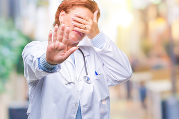 Senior caucasian doctor woman wearing medical uniform over isolated background covering eyes with hands and doing stop gesture with sad and fear expression. Embarrassed and negative concept.