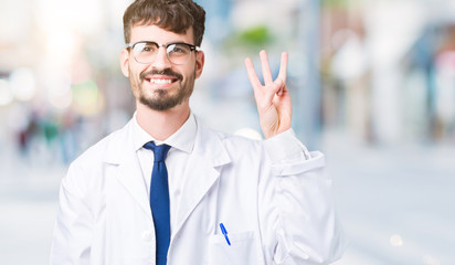 Young professional scientist man wearing white coat over isolated background showing and pointing up with fingers number three while smiling confident and happy.