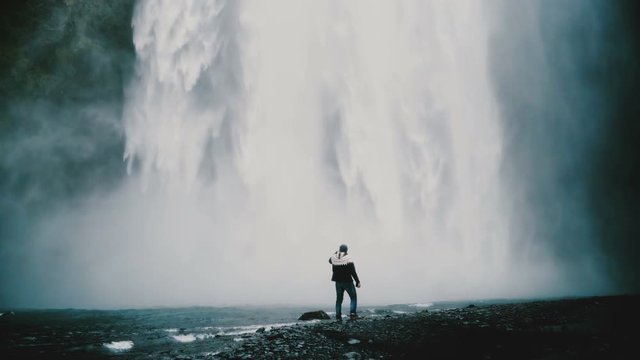 Young handsome man walking near the powerful Gljufrabui waterfall in Iceland alone, enjoying landscape.