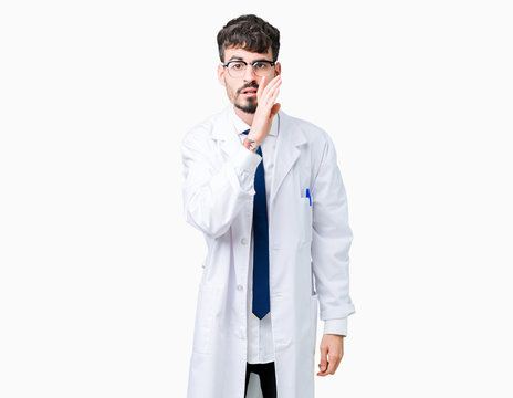 Young professional scientist man wearing white coat over isolated background hand on mouth telling secret rumor, whispering malicious talk conversation