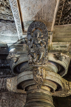 Halebidu, Karnataka, India - November 2, 2013: Hoysaleswara Temple of Shiva. Closeup of Madanakai or Salabhanjika, a dancing girl statue against ceiling on top of pillar. Gray brownish stone.