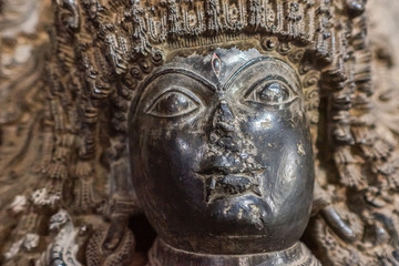 Fototapeta na wymiar Halebidu, Karnataka, India - November 2, 2013: Hoysaleswara Temple of Shiva. Closeup of damaged Dwarapalaka face at entrance to Mandapam of main temple building. Gray brown stone. 
