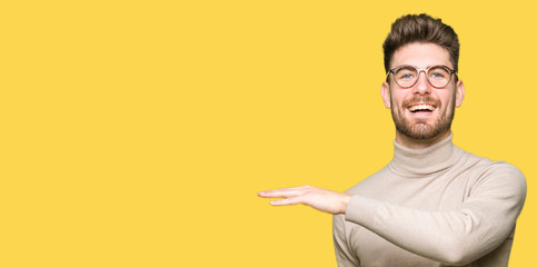 Young handsome business man wearing glasses gesturing with hands showing big and large size sign, measure symbol. Smiling looking at the camera. Measuring concept.