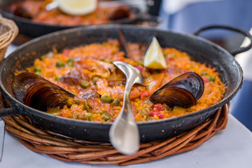 Delicious seafood paella on an iron pan. Rice, lemon, mussels, shrimp and vegetables