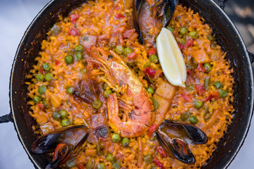 Delicious seafood paella on an iron pan. Rice, lemon, mussels, shrimp and vegetables