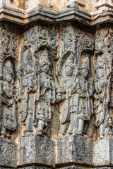 Fototapeta na wymiar Halebidu, Karnataka, India - November 2, 2013: Hoysaleswara Temple of Shiva. Series of corner statues on side of the temple structure in gray stone and some brown background.