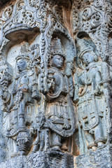 Halebidu, Karnataka, India - November 2, 2013: Hoysaleswara Temple of Shiva. Closeup of corner statues on side of the temple structure in gray stone and some brown background.