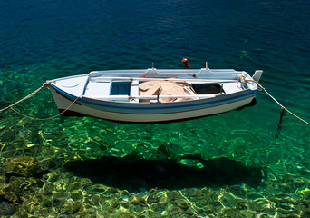 Fototapeta premium Fishing boat seems floats on crystal clear water at Symi island, Greece