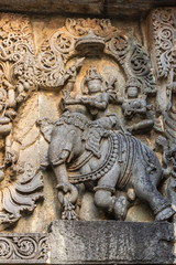 Fototapeta na wymiar Halebidu, Karnataka, India - November 2, 2013: Hoysaleswara Temple of Shiva. Closeup of statue on side of main sanctuary, where Lord Shiva and Devi Parvati sit on elephant. Gray stone with brown back.