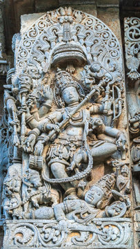 Halebidu, Karnataka, India - November 2, 2013: Hoysaleswara Temple of Shiva. Closeup of statue on side of main sanctuary, where Lord Shiva, Nataraja, dances on the body of demon Apasmara. Bluish gray 