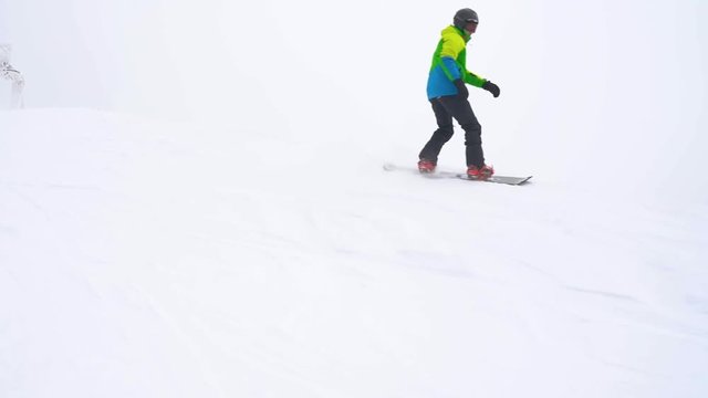 Extreme snowboarder riding fresh powder snow down the steep mountain slope. Slow motion