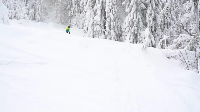 Extreme snowboarder riding fresh powder snow down the steep mountain slope
