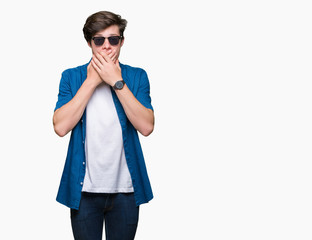 Young handsome man wearing sunglasses over isolated background shocked covering mouth with hands for mistake. Secret concept.