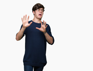 Fototapeta premium Young handsome man wearing glasses over isolated background afraid and terrified with fear expression stop gesture with hands, shouting in shock. Panic concept.