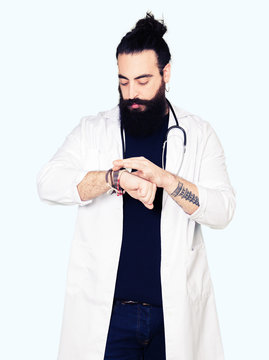 Doctor with long hair wearing medical coat and stethoscope Checking the time on wrist watch, relaxed and confident