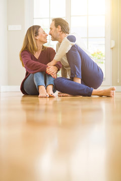 Beautiful romantic couple sitting together on the floor kissing in love at home