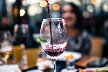 red wine  filled wine glass in front of blurred bokeh young gouple