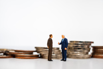 Miniature people, couple businessman standing on pile coins background using as business corporation and financial concept