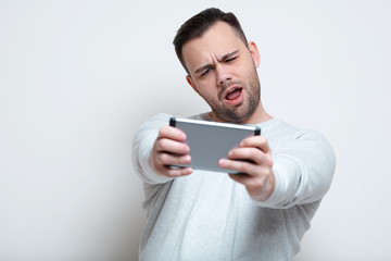 Happy screaming man playing video games on smartphone over white background