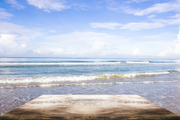 empty wood table on blurred of people walk on the beach with sunrise, warm tone