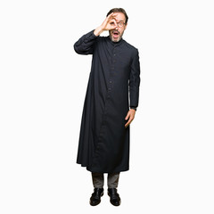 Middle age priest man wearing catholic robe doing ok gesture shocked with surprised face, eye...
