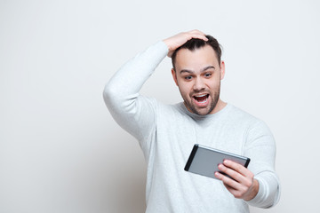 Surprised shocked young man using tablet over white background.