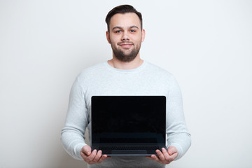 Portrait of young man holding laptop over white background.