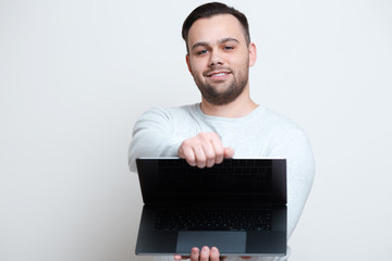 Portrait of young happy man opening laptop over white background.