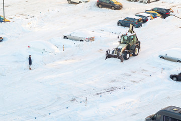 Tractor removes snow in the parking lot after a snowfall