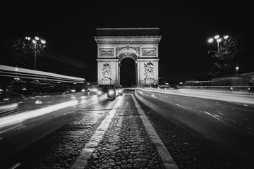 Fototapeta na wymiar Traffic on Avenue des Champs-Élysées and the Arc de Triomphe at night in Paris, France.
