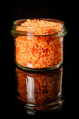 closeup small glass jar with orange organic sea salt