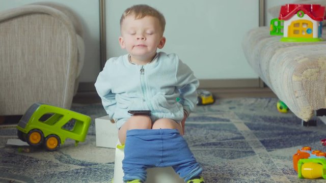 Adorable boy with a smartphone during potty training on the room.