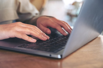 Closeup image of hands using and typing on laptop keyboard on the table