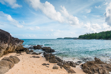 Fototapeta na wymiar Brown rocks along the beach that leads to the blue sea