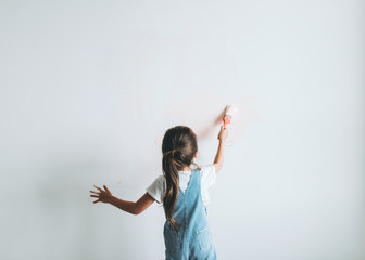 Young girl painting the walls pink