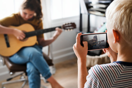 Brother recording his sister playing the guitar