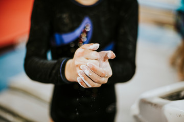 Young gymnast applying a powdered chalk to her palms