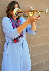 Female jazz trumpet player blowing her horn outside.