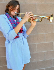 Female jazz trumpet player blowing her horn outside.