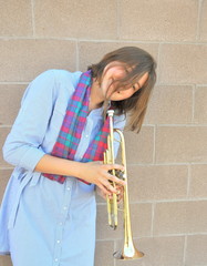Female jazz trumpet player blowing her horn outside.