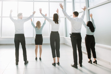 rear view.happy business team standing in bright new office.