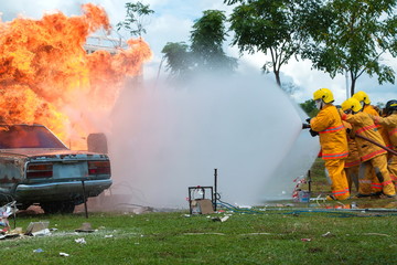 Firefighter,firefighter training, fireman using water and extinguisher to fighting with fire flame in accident car on road