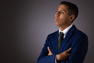 Hispanic Teenager Boy Well Dressed on Gray Background Looking Away from Camera and Deeply Pondering