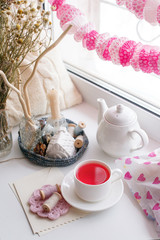 Still life of used candles, tea, teapot, pillow on a white table near window, romance morning feminine concept