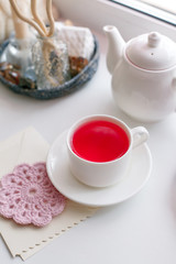 Obraz na płótnie Canvas Cup of tea and teapot on white windowsill, morning springtime concept