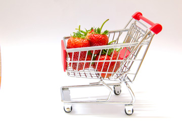 Fresh strawberries in shopping cart on white background.